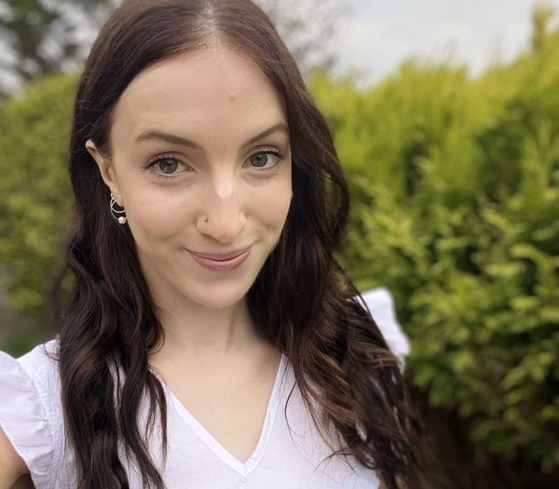 Picture of Annie smiling against a background of trees